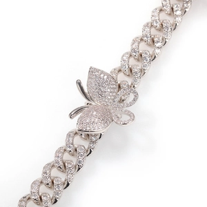 Macro detail of silver Cuban link necklace featuring a butterfly pendant with micro-pave zircons