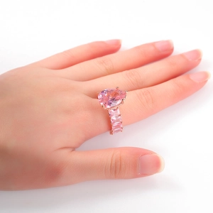 Elegant rose gold ring featuring a large pear-cut pink gem and baguette side stones