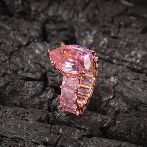 Macro shot of luxury rose gold ring with pear-cut pink gem and baguette-cut pave band