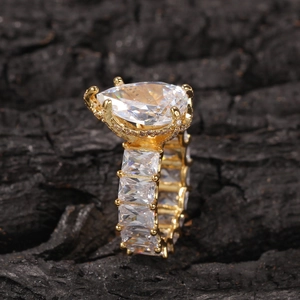 Close-up of golden ring featuring a pear-shaped zircon and rectangular stones on dark background