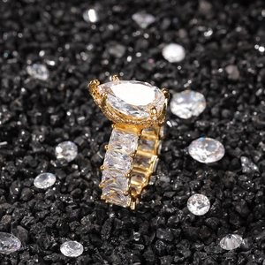 Close-up of gold pear-cut ring with rectangle side stones on black crushed stones