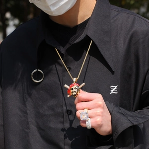Detail of gold skull pendant with zircon stones and matching rings on male model