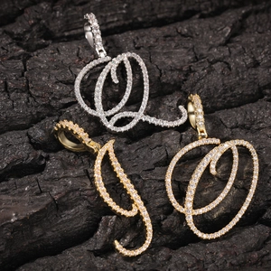 Vue macro des pendentifs lettres cursives sertis de zircons en or et argent poli