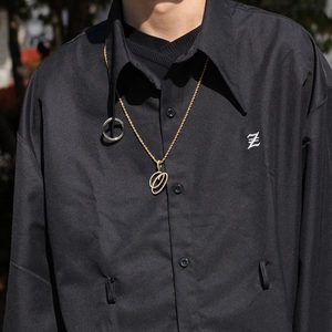Gros plan d'un collier chaîne torsadée dorée avec pendentif lettre O sur modèle