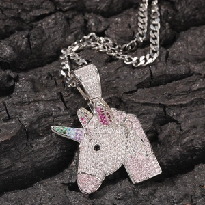 Makro-Detail des silbernen Einhorn-Anhängers mit bunten Zirkonsteinen auf Steinoberfläche