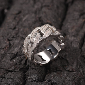 Bague chaîne cubaine argentée hip hop pavée de zircons sur un fond de bois sombre