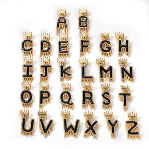 Vue macro des pendentifs couronne A-Z hip hop en or avec effet goutte d'huile noire