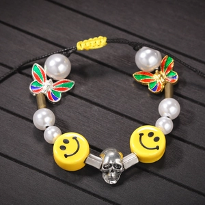 Detail of beaded bracelet with pearls, yellow smiley faces, and a silver skull charm