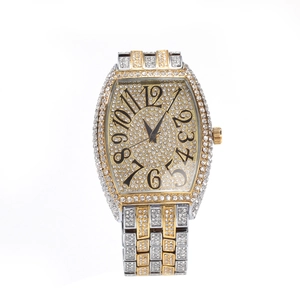 Macro shot of iced out tonneau watch dial with paved diamonds and gold numerals