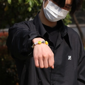 Close-up of hip-hop bracelet with pearls, smiley beads, and skull charms on wrist