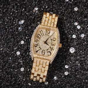 Macro shot of gold tonneau iced out watch with full diamond setting on black stone background