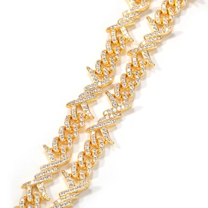 Detailed close-up of a gold hip-hop chain with barbed wire links and sparkling zircons