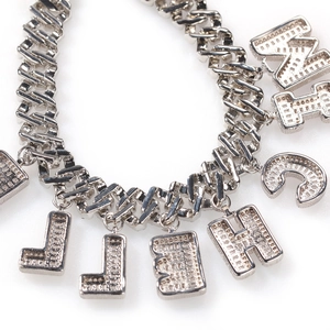 Detail of silver Cuban chain necklace with custom crystal letter pendants in hip hop style