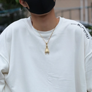 Detailopname van gouden punk hip hop stekker hanger ketting voor heren op wit sweatshirt