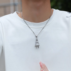 Detail van hiphop-ketting met stekker-hanger en zilveren kristallen op een witte trui