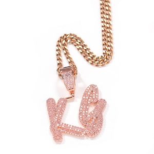 Detail of rose gold custom script letter pendant with pink zircon and Cuban chain link