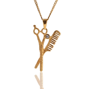 Gros plan du pendentif ciseaux et peigne dorés avec zircon blanc sur chaîne longue