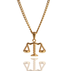 Vue détaillée d'un pendentif balance de la justice en or poli sur une longue chaîne