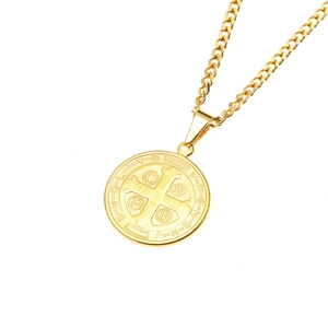 Detalle de medalla de San Benito dorada con cadena de eslabones cubanos de acero inoxidable