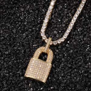 Close-up of gold iced-out padlock pendant with tennis chain on black mineral stones