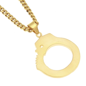 Detailed macro view of gold-plated stainless steel handcuffs pendant on a cuban chain
