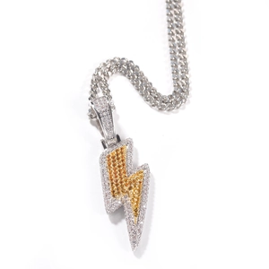 Detailed close-up of iced out lightning bolt pendant with yellow zircons on cuban chain