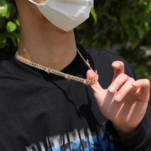 Goldene Iced-Out Gliederkette mit rosa Schmetterlingsanhängern am Hals getragen