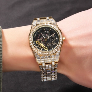 Détail d'une montre mécanique squelette dorée sertie de cristaux au poignet