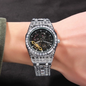 Vue détaillée d'une montre mécanique glacée avec pierres carrées et cadran squelette