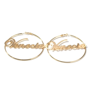 Detailed close-up of large gold hoop earrings with Venecia script nameplate detail