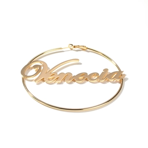 Close-up of gold hoop earring featuring Venecia script lettering and classic clasp