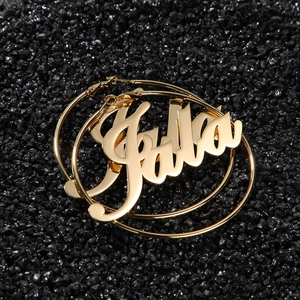 Macro detail of large golden hoop earrings featuring artistic Galla nameplate design