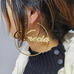 Close-up of a large gold hoop earring featuring a custom Venecia script nameplate detail