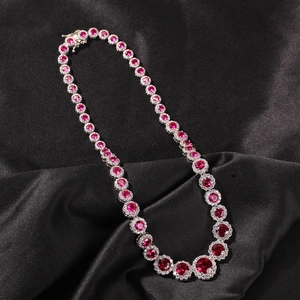 Makroaufnahme einer Silberkette mit runden rosa Zirkonia auf schwarzem Satinstoff