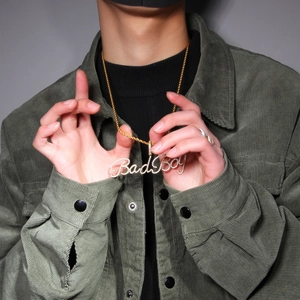 Nahaufnahme einer goldenen Kordelkette mit Bad Boy Buchstaben Anhänger und Zirkonia