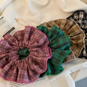 Detailed macro view of four plaid fabric scrunchies in pink green coffee and monochrome