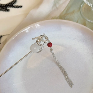 Vue détaillée du pic à cheveux dragon en argent avec disque de jade blanc et long gland