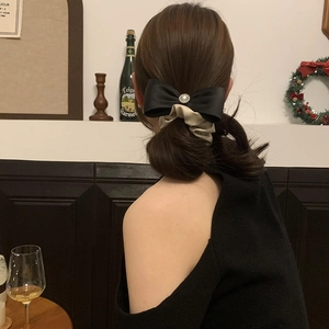 Detail of elegant satin bow hair scrunchie with pearl center on woman's hairstyle