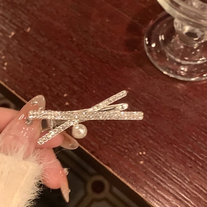 Barrette argentée élégante avec strass brillants et perle blanche sur fond en bois
