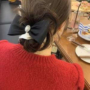 Elegant black satin bow hair tie featuring a pearl center for a chic ponytail accessory