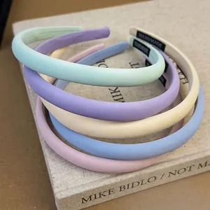 Cinq serre-têtes en éponge rembourrée aux couleurs macaron empilés sur un livre