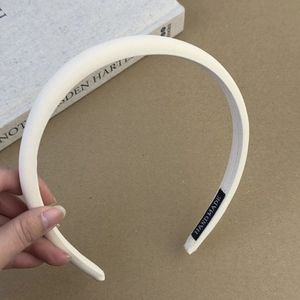 Détail d'un serre-tête en tissu crème avec étiquette fait main et texture épurée