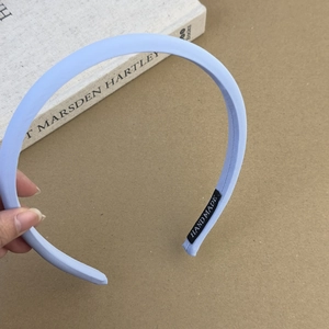 Gros plan détaillé du serre-tête en tissu bleu clair avec étiquette faite main