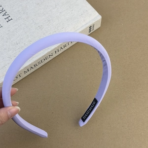 Gros plan d'un serre-tête en tissu violet avec texture fine et étiquette fait main