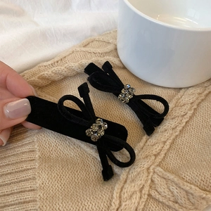 Set of two black velvet bow hair clips with crystal center on a cozy knit background