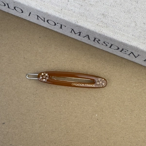 Détail de la barrette en acétate ambre avec strass et lettrage doré Creation France