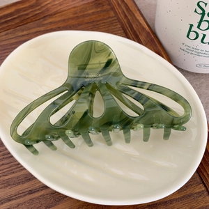 Elegant emerald marble acetate hair claw clip with triangle cutout on a ceramic plate