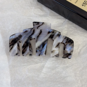 Gros plan d'une grande pince à cheveux en acétate avec motif de marbre noir et blanc