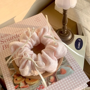 Sweet pink knitted scrunchie with white satin bows on a warm aesthetic background