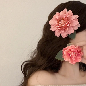 Close-up of a dusty pink silk camellia hair claw clip with lifelike green leaf details